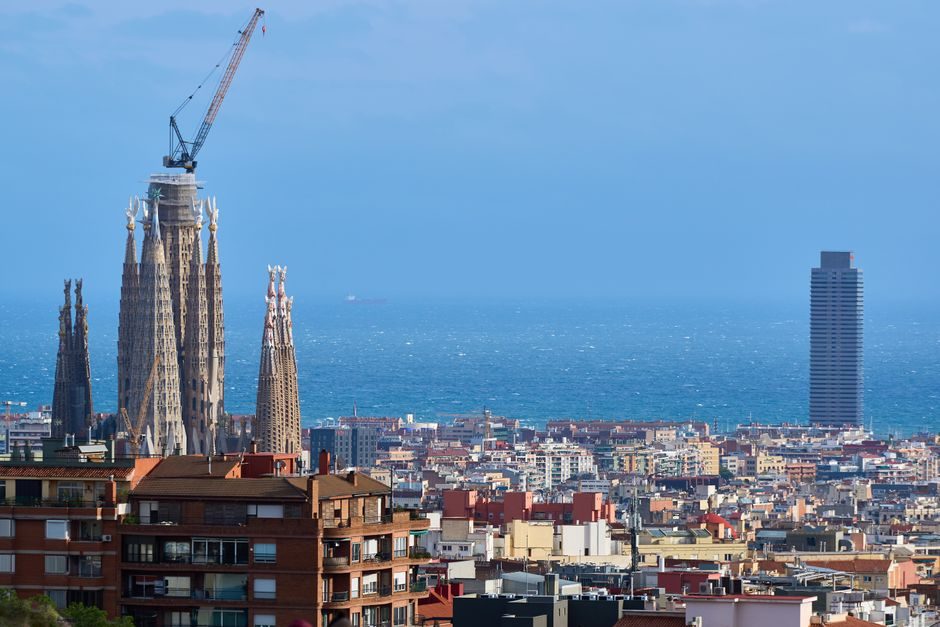 Les tours de la Sagrada Família au-dessus des toits de Barcelone, la Méditerranée au fond